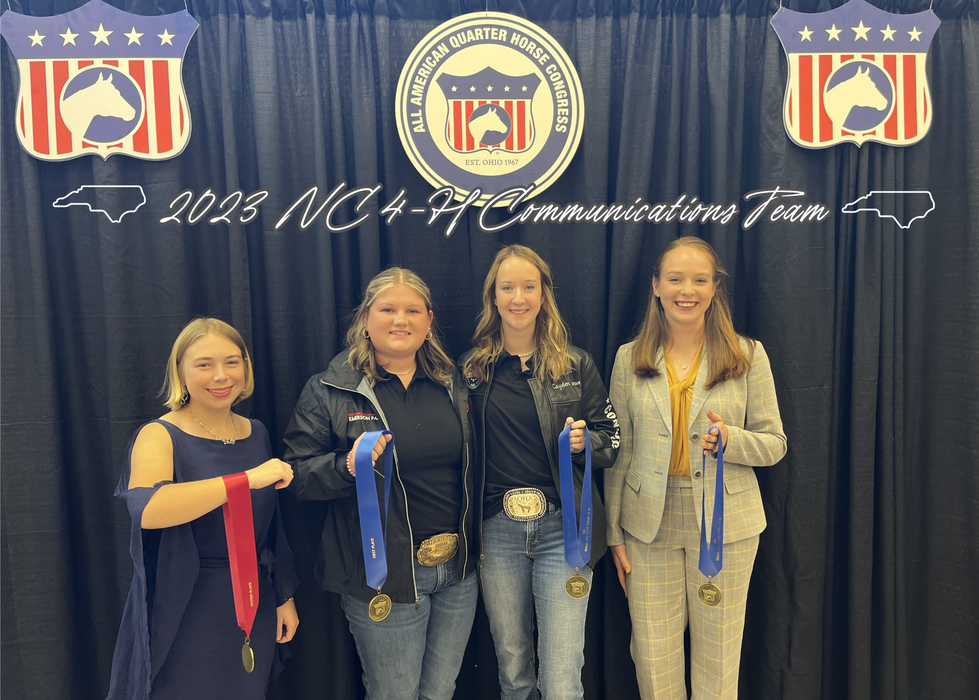 Four young women holding medals under banner reading 2023 NC 4-H Communications Team