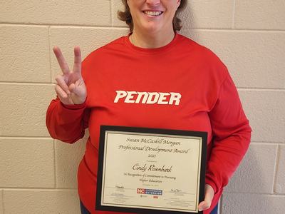 A woman in a Pender sweatshirt holds an award.