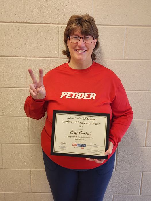 A woman in a Pender sweatshirt holds an award.
