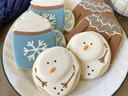 Plate of decorated winter cookies: snowmen, blue hot-cocoa mugs, and patterned mittens