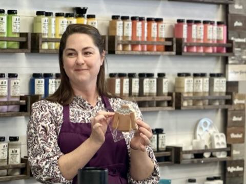 A woman displays an example of a sugar cookie sweater.