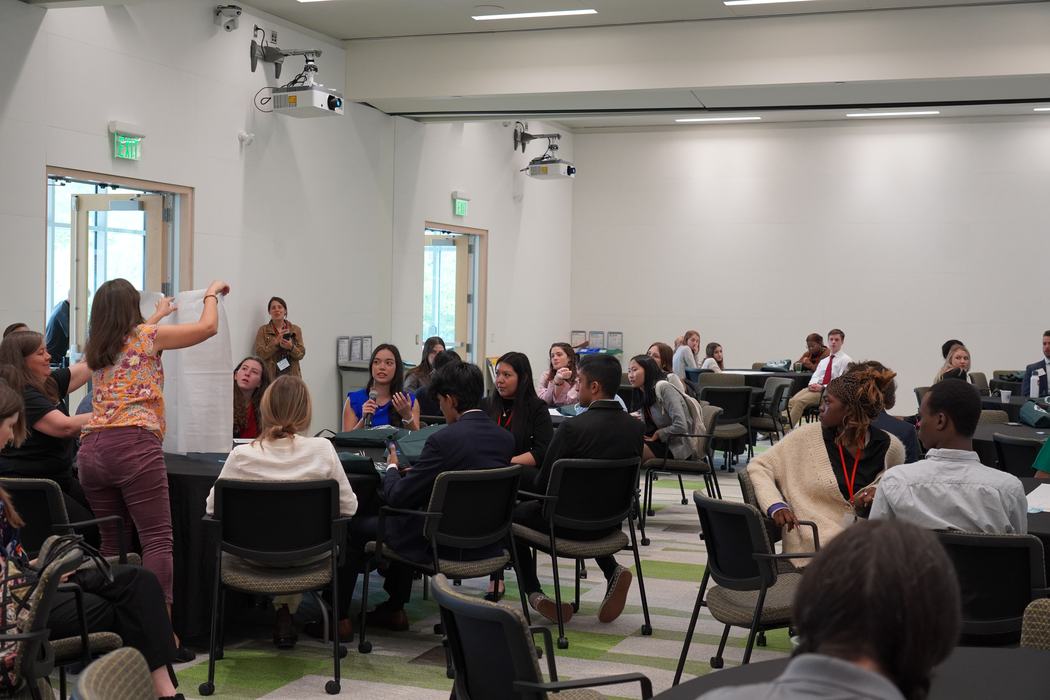 youth gathered around a table discussing ideas