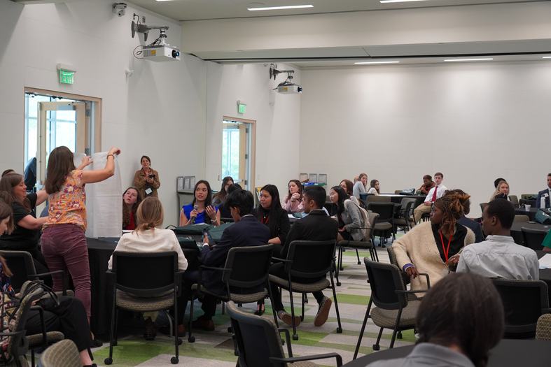 youth gathered around a table discussing ideas