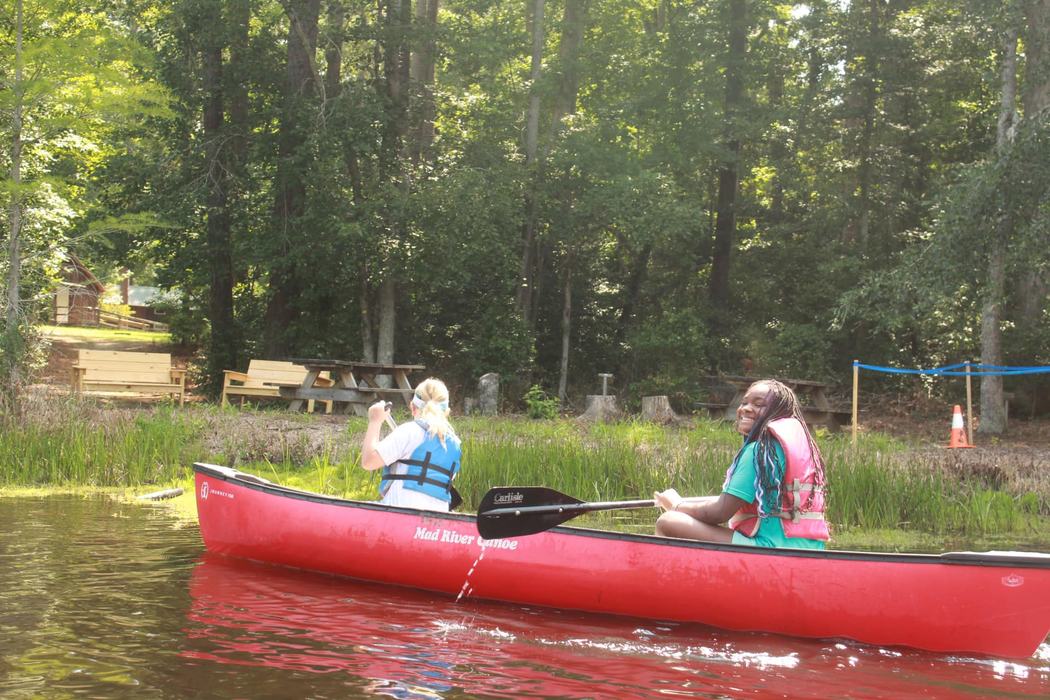 Two girls wearing life jackets in a canoe at Millstone 4-H Camp