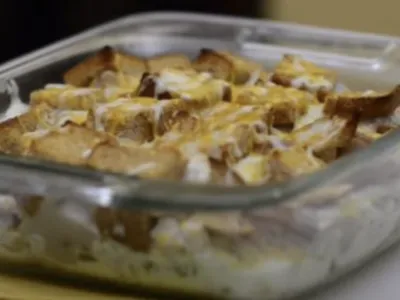 Glass baking dish of bread pudding with toasted bread cubes and creamy topping