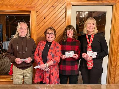 Four adults standing indoors holding small white cards, wood-paneled wall and door behind