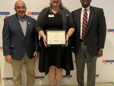 Three people standing; center person holds certificate reading "New EFNEP Educator Award"