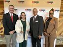 Four people standing at NC Cooperative Extension backdrop; second person holds two glass awards.