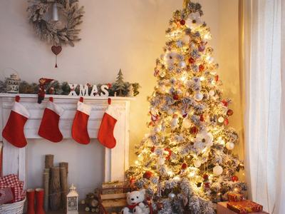 Christmas tree with lights and ornaments beside mantel displaying four red Christmas stockings