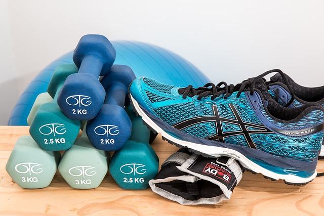 workout weights stacked up beside a pair of sneakers in a gym.