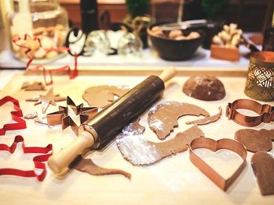 Cookie cutters, with raw cookie dough and flour on top of a counter with a rolling pin.