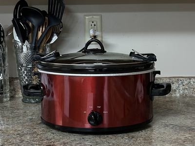 Red slow cooker on kitchen counter with dial labeled Off, Low, High, Warm