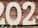 White wooden numbers "2024" on wooden background with blue succulent and eucalyptus accents