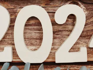 White wooden numbers "2024" on wooden background with blue succulent and eucalyptus accents