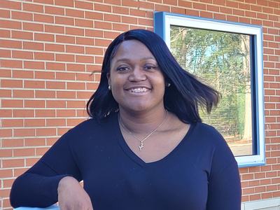 A woman standing in front of a brick building.