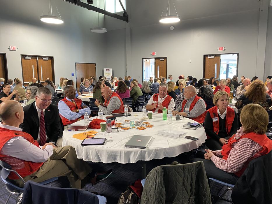 Extension employees sitting at round tables discussing various topics in pairs.