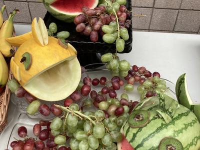 Carved watermelon and melon fish sculptures surrounded by red and green grapes