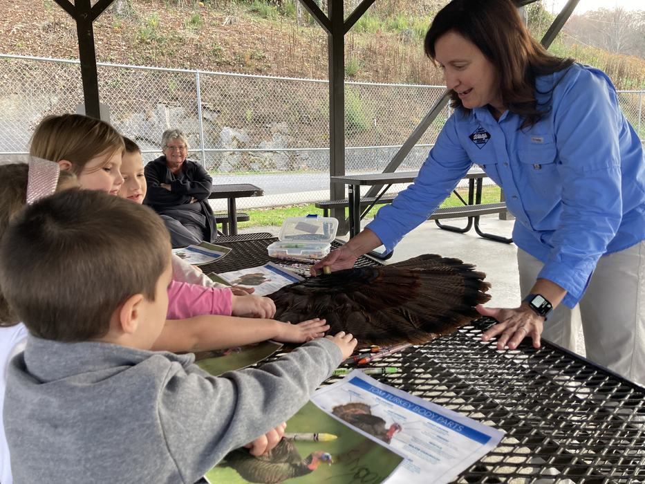 4-H outdoor club. Children interact with a preserved turkey wing while learning from a wildlife expert. 