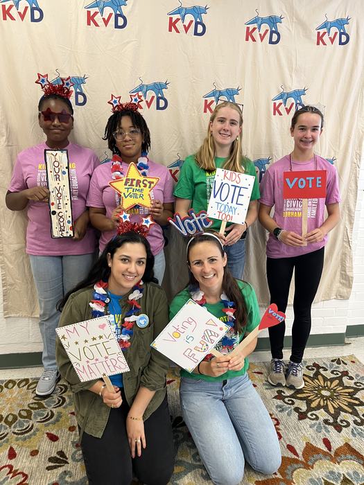 A group of girls hold signs encouraging others to vote.
