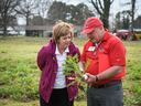 Man in red NC State shirt and cap showing a pulled root vegetable to woman in purple jacket