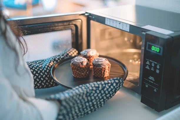 an asian chinese female putting cakes on a plate to microwave to heat up wearing kitchen glove