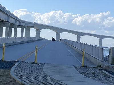 Curving elevated bridge rising toward horizon with small figures on the roadway