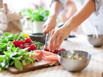 A person prepares food be slicing meat on a cutting board.