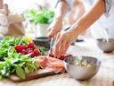 A person prepares food be slicing meat on a cutting board.