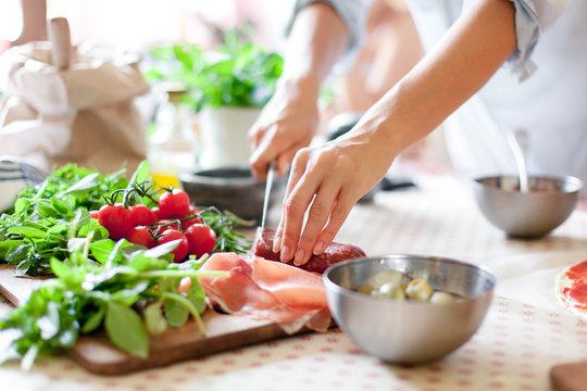 A person prepares food be slicing meat on a cutting board.