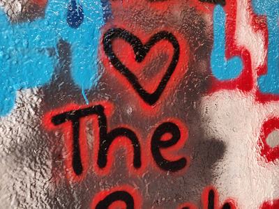 Graffiti on textured wall reading "PSSI ♥ The Pack" in black spray paint with red outline