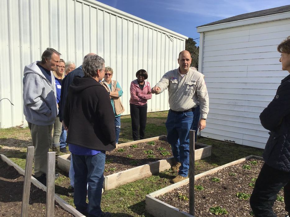 Daniel Simpson, CED for Pamlico County Cooperative Extension, is pointing out garden beds behind the Extension building to new Master Gardener students.