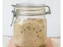 Glass jar containing active, bubbly sourdough starter fermenting
