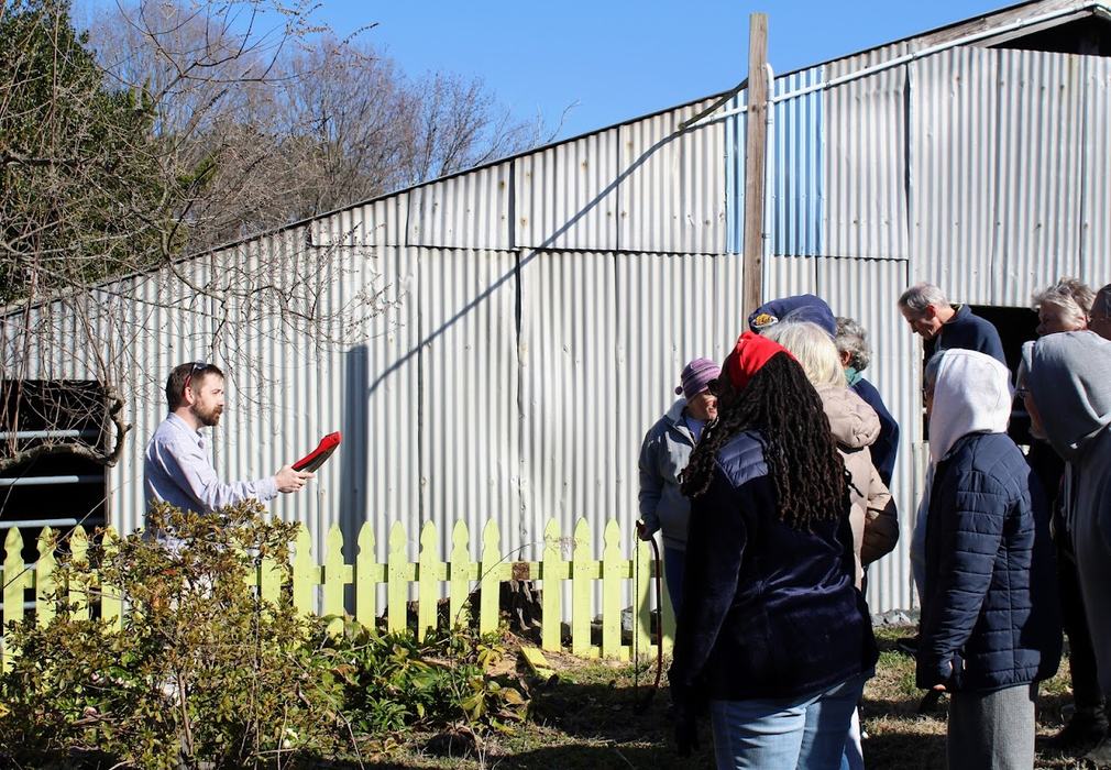 A man holds a red tool in front of a group of adult students.