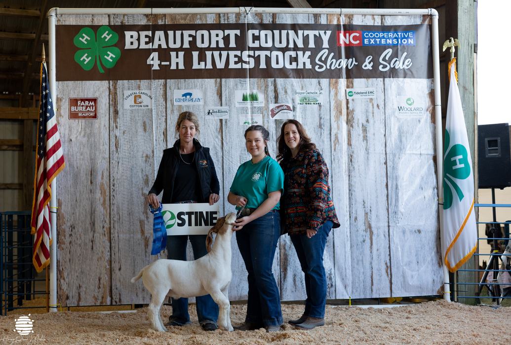 Adults and a kid posing with a goat.