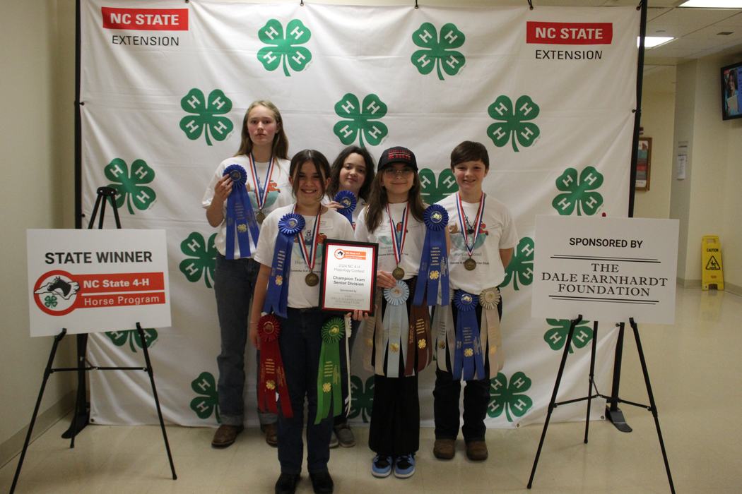 Five youths with ribbons and plaque before 4-H backdrop; signs: STATE WINNER and DALE EARNHARDT FOUNDATION