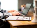 Person sitting at computer with a clip board
