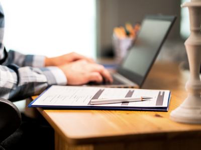 Person sitting at computer with a clip board