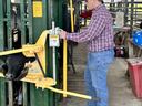 A man works a machine with a cow inside of it.