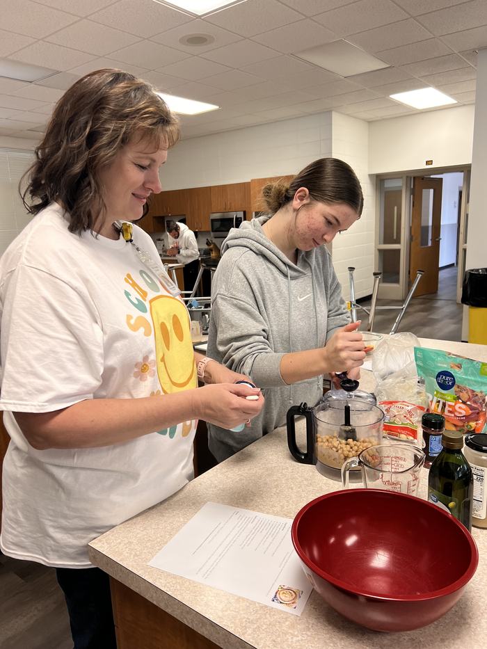 Women use a food processor as part of food preperation.