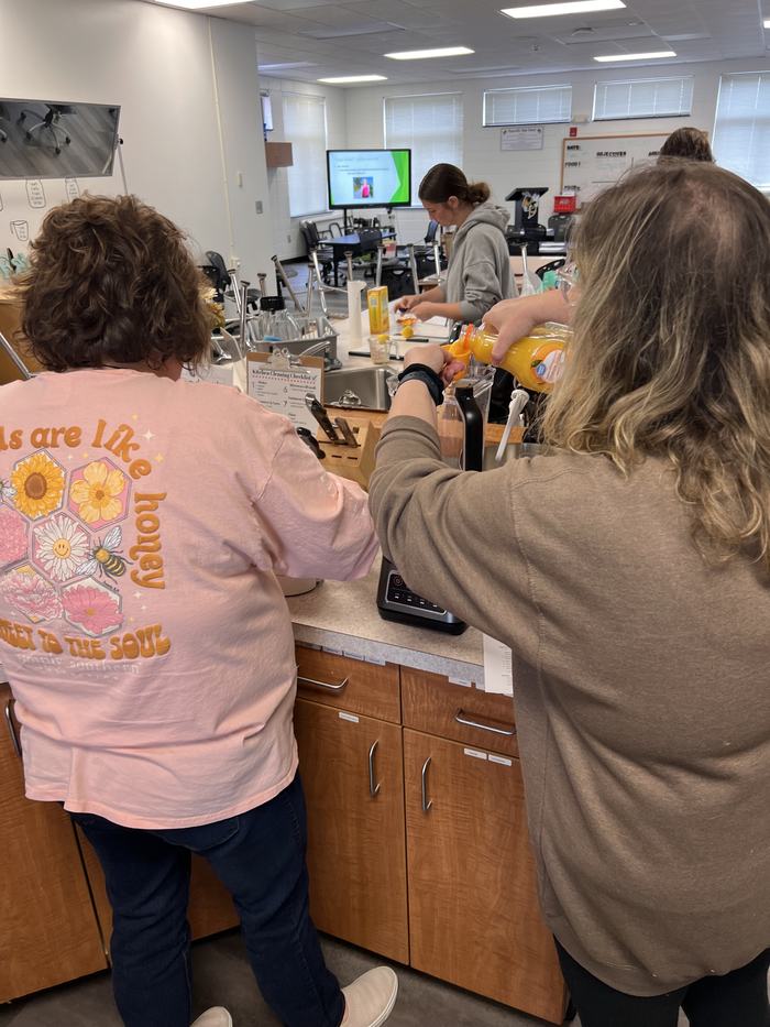 A woman measures orange juice in a kitchen classroom.