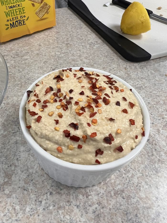 A ramekin with humus and chili flake.