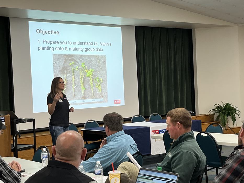 Woman presenting; slide reads "Objective: Prepare you to understand Dr. Vann's planting date & maturity group data"