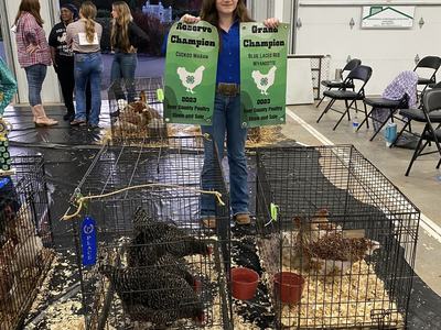 A girl holds 4-H Banners declaring her the Reserve champion and Grand champion.