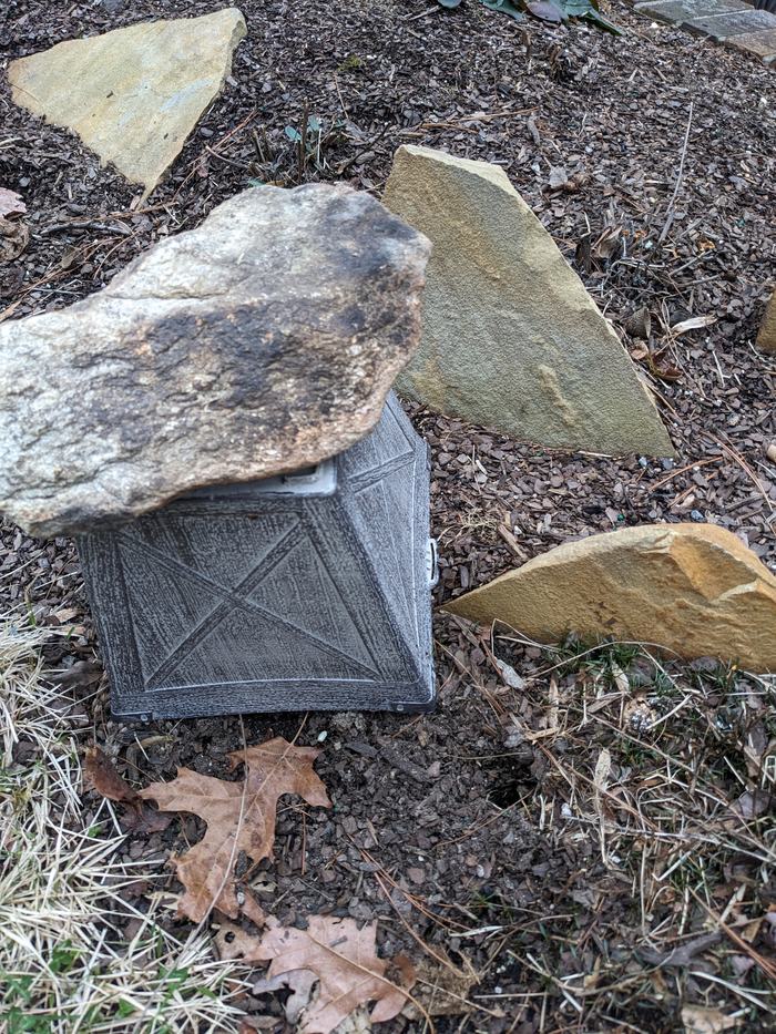 A plant pot, repurposed to cover the trap and hole.