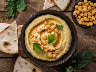 healthy homemade chickpea hummus with olive oil and smoked paprika, wooden background, top view