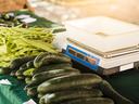 Stack of cucumbers and green beans beside an empty digital produce scale