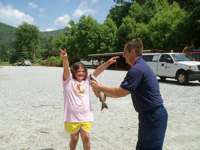 A 4-H volunteer helping a 4-Her fish