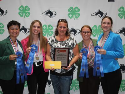 Five people holding plaque, blue ribbons and envelope at 2024 NC 4-H Horse Judging Contest