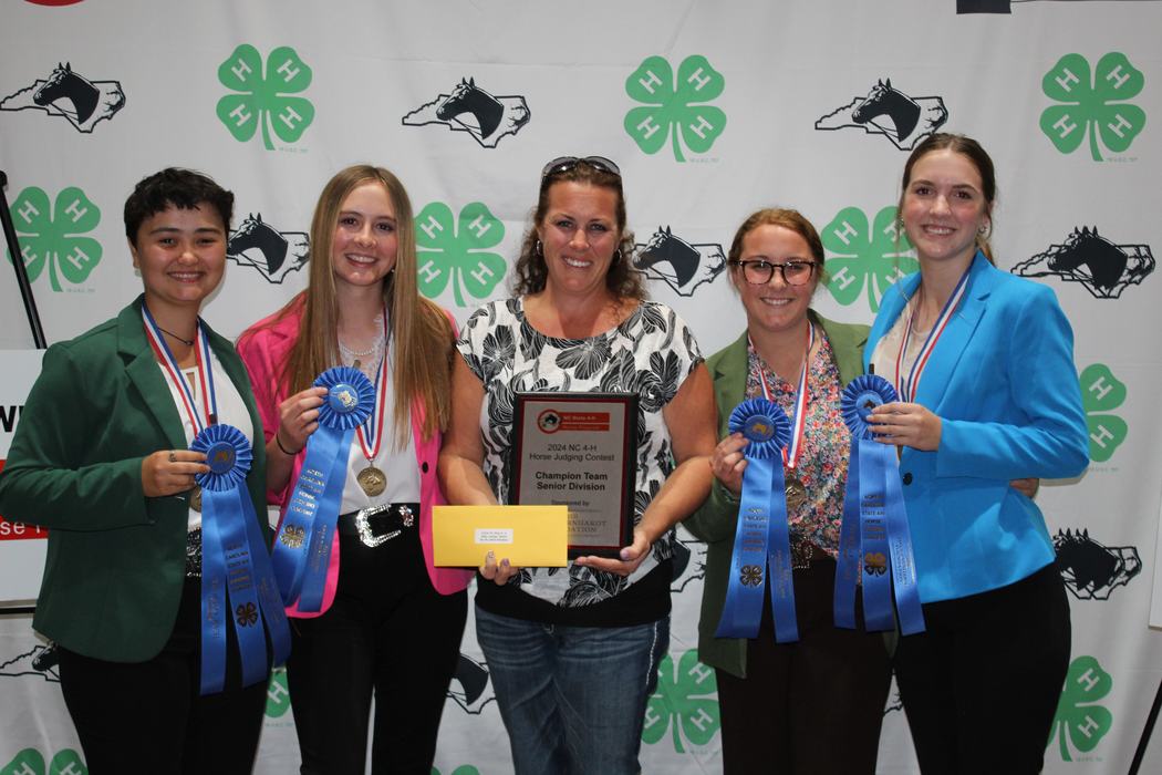 Five people holding plaque, blue ribbons and envelope at 2024 NC 4-H Horse Judging Contest
