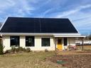 Single-story house with large rooftop solar panels and a yellow front door